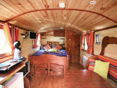 Hébergement insolite en roulotte en bois, décor chaleureux et coloré.