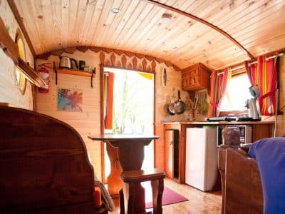 Intérieur chaleureux dune roulotte en bois, avec cuisine et décor coloré.
