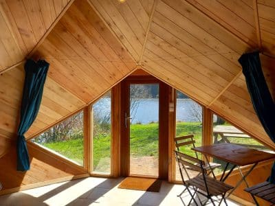 Hébergement insolite en Auvergne : cabane en bois avec vue sur le lac et lumière naturelle.
