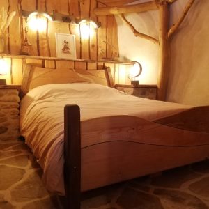 Chambre en bois dans un hébergement insolite, ambiance chaleureuse et rustique.