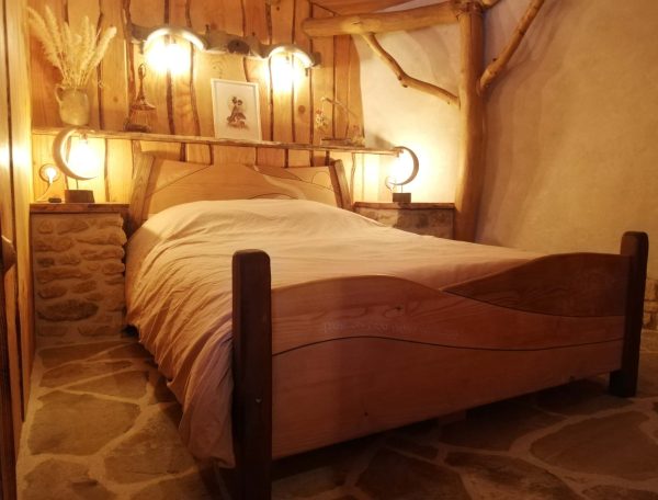Chambre dhôtes chaleureuse avec lit en bois et murs en pierre.