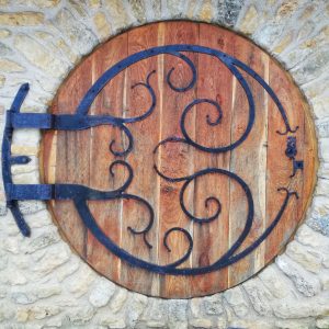 Porte en bois ronde dun gîte, ornée de ferronneries artistiques.