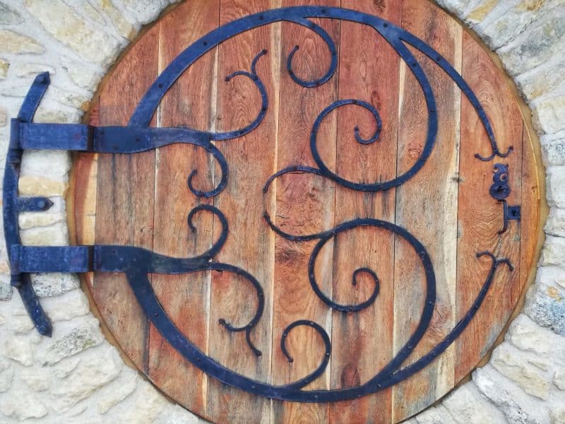 Porte en bois ronde dun gîte, ornée de ferronneries artistiques.