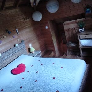 Chalet en bois romantique avec lit décoré de pétales et lanternes suspendues.