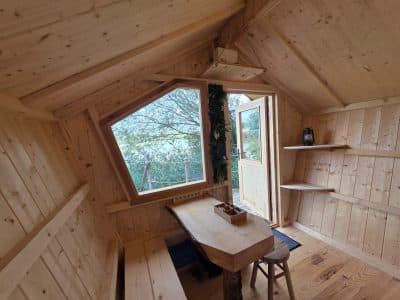 Cabane en bois avec vue panoramique sur la nature, intérieur chaleureux et lumineux.