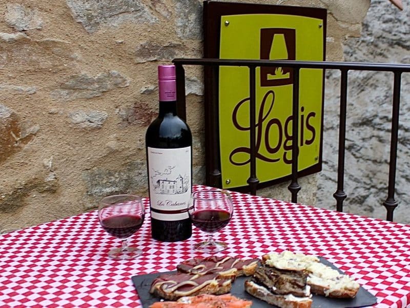 Logis accueillant avec table à carreaux, vin rouge et planche de tapas savoureuses.