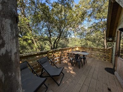 Cabane perchée en Languedoc-Roussillon avec terrasse en bois et chaises longues.