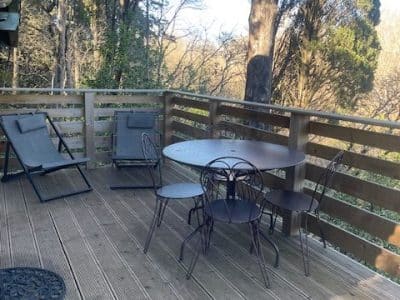 Cabane perchée en Languedoc-Roussillon avec terrasse en bois et chaises confortables.