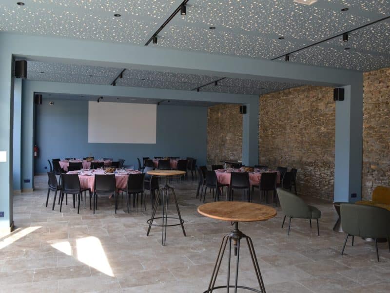 Salle de réception moderne avec murs en pierre et tables élégamment dressées.