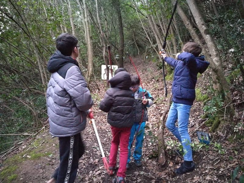 Gîte en pleine nature, enfants explorant un sentier boisé avec des outils.