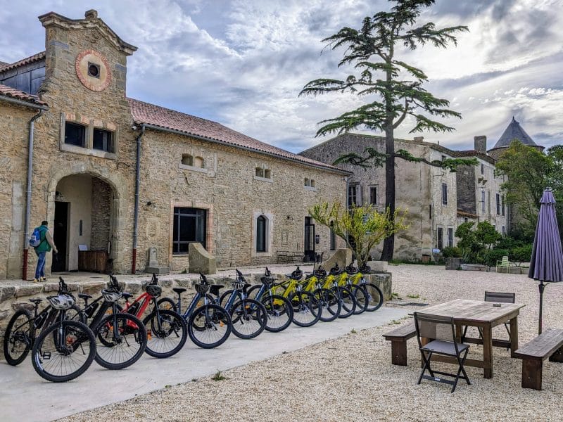 Gîte rural avec vélos en location, entouré de bâtiments en pierre et dun jardin paisible.
