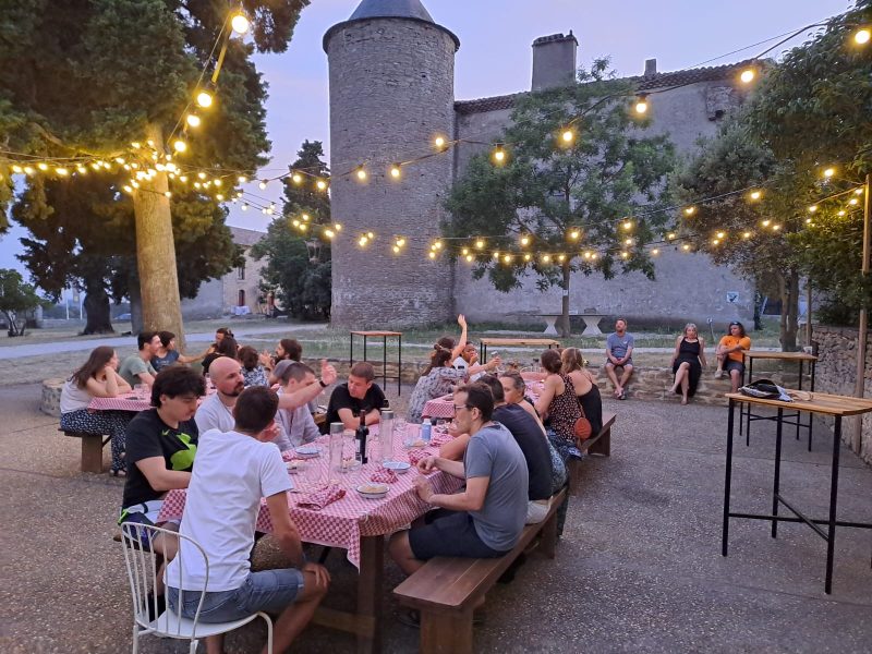 Dîner convivial en extérieur dans un gîte, sous des guirlandes lumineuses.