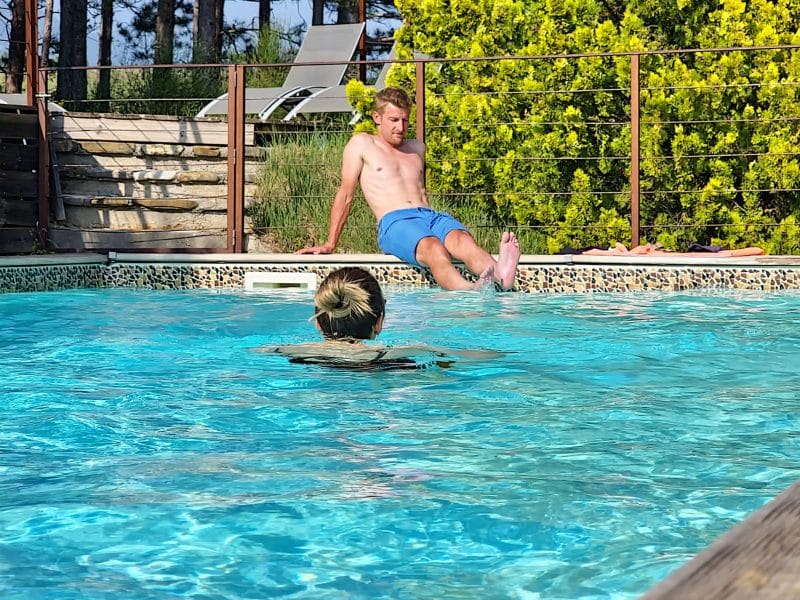 Hébergement avec piscine, un homme se détend au bord de leau sous un soleil radieux.