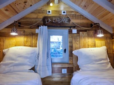 Cabane en bois avec lits jumeaux et décor chaleureux en Provence-Alpes-Côte dAzur.