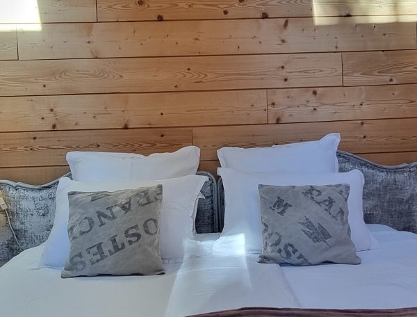 Chalet cosy avec murs en bois, lit douillet et coussins décoratifs.