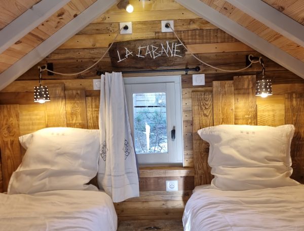 Chalet en bois avec deux lits séparés et une décoration chaleureuse.