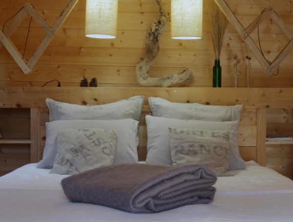 Chalet en bois chaleureux avec literie confortable et lampes suspendues.