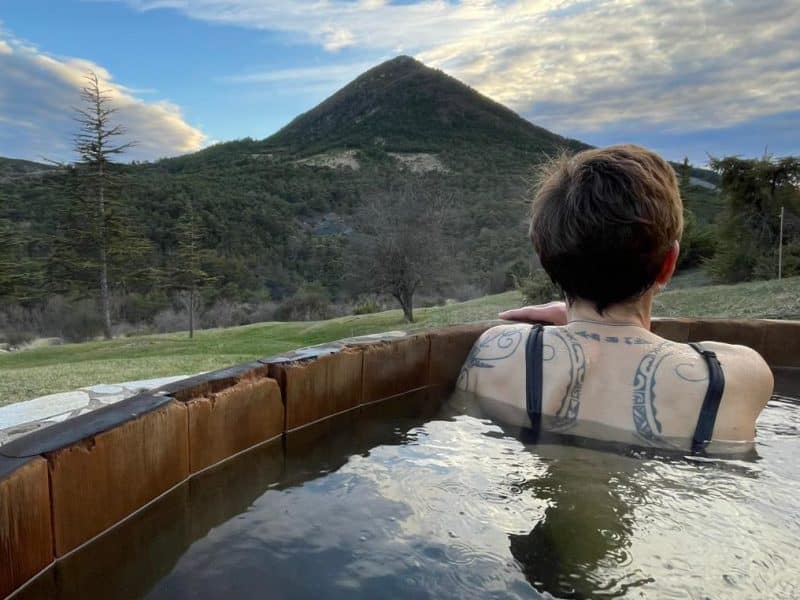 Hébergement en pleine nature avec baignoire extérieure, vue sur la montagne.
