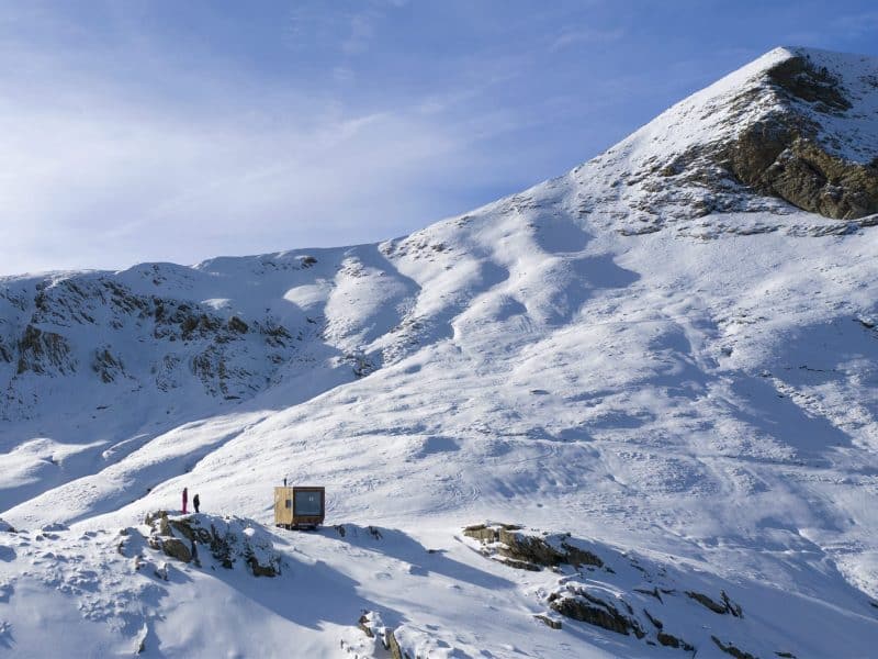 Chalet en montagne, entouré de neige, avec un paysage alpin spectaculaire.