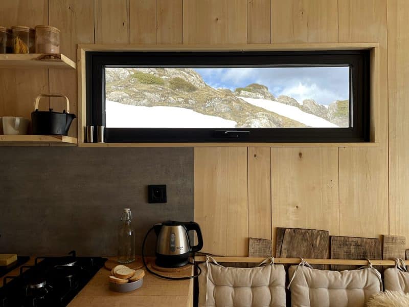 Cabane moderne avec vue sur les montagnes, intérieur en bois chaleureux.