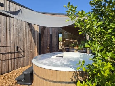 Hébergement insolite en Auvergne-Rhône-Alpes avec jacuzzi extérieur et verdure environnante.