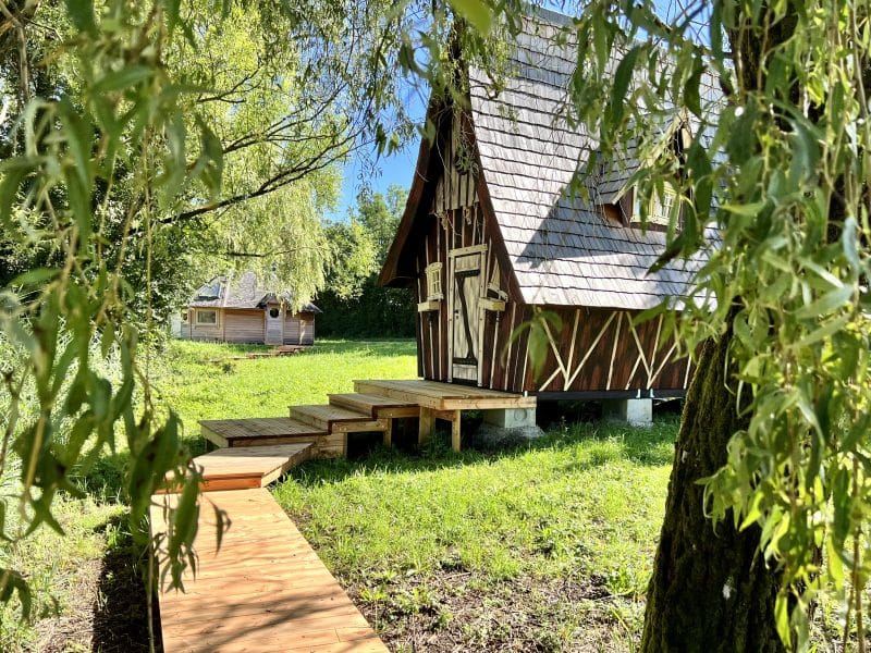 Cabane en bois typique avec un chemin en bois, entourée de verdure en Auvergne-Rhône-Alpes.