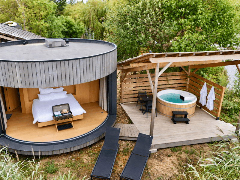 Hébergement insolite en bulle avec jacuzzi, entouré de verdure et au bord de leau.