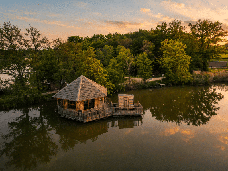 Cabane sur leau à Auvergne-Rhône-Alpes, entourée de verdure et reflet dans le lac.
