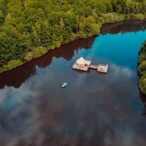 Cabane flottante au bord dun lac, entourée de verdure luxuriante.